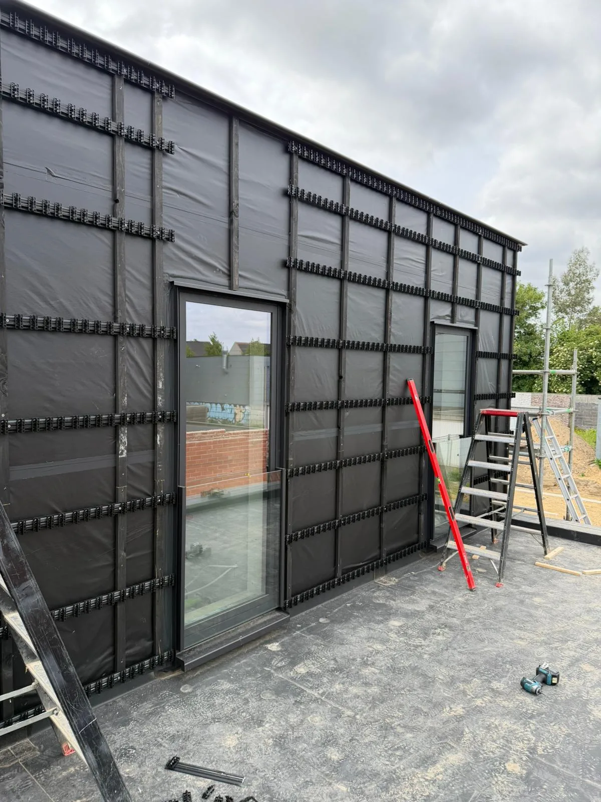 Façade sombre en cours de bardage bois